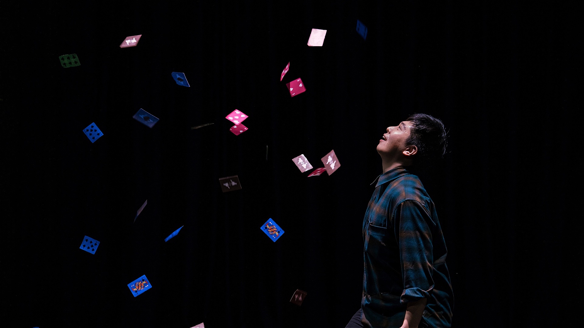 Dazed and confused Stage photo／Photographer: Wong de. A man staring at a variety of playing cards floating through the air.